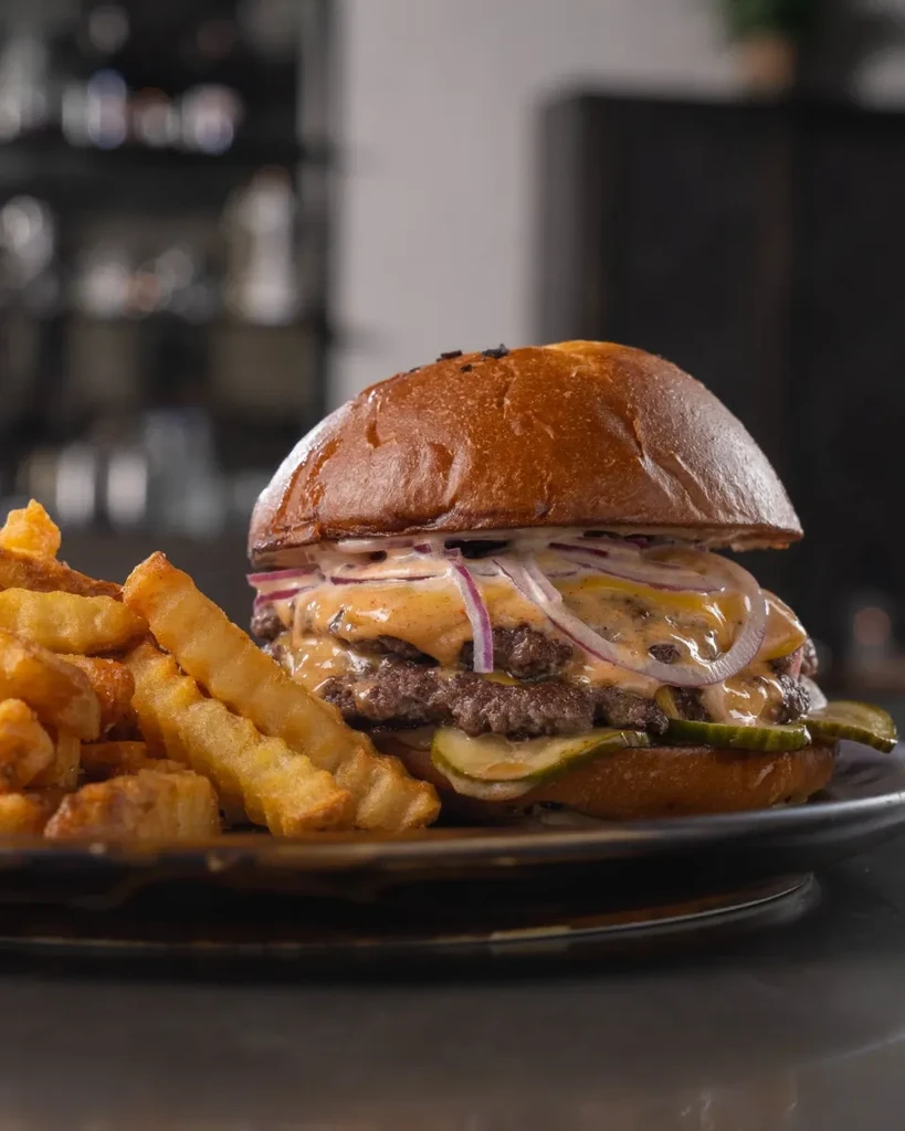 Double cheeseburger with melted cheese, onions, pickles, and crinkle-cut fries.
