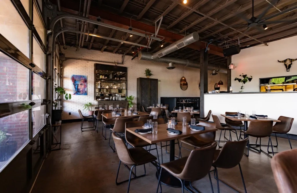Empty industrial-chic restaurant interior with wooden tables and brick walls.