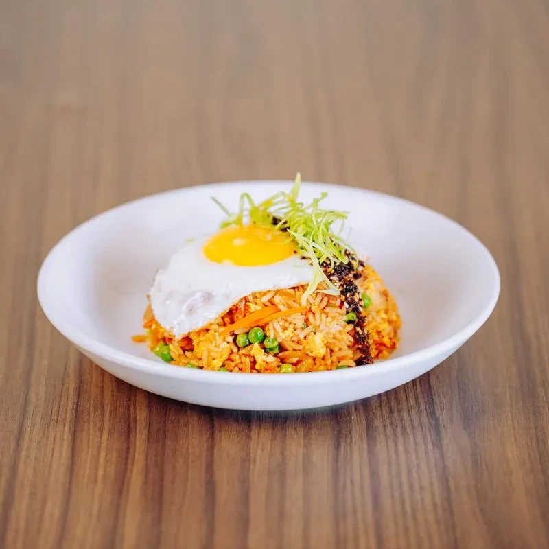 Fried rice with sunny-side-up egg, green onions, and chili oil in a bowl.