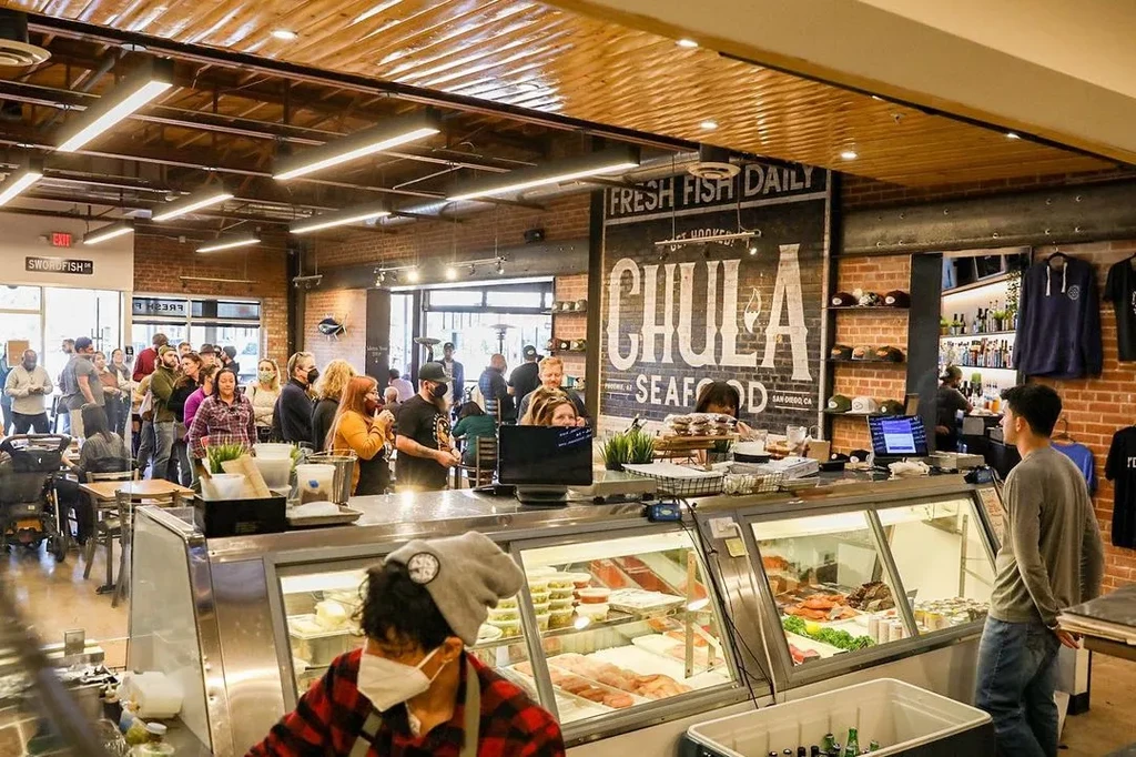 Lively San Diego seafood market with fresh fish counter and customers.