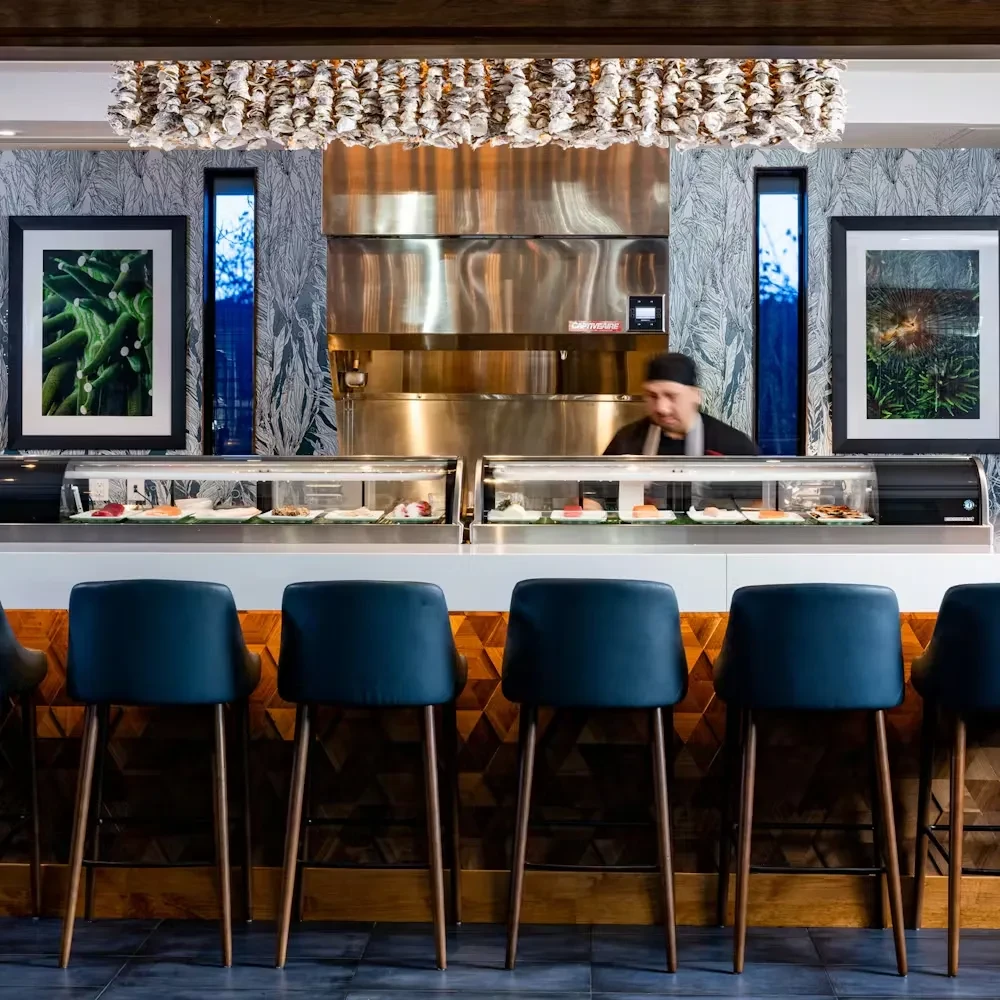Modern upscale sushi bar with shell chandelier and patterned wood.