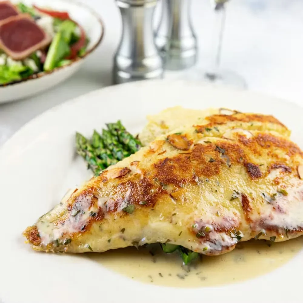 Plated fillet with creamy sauce, almonds, asparagus, and mashed potatoes.