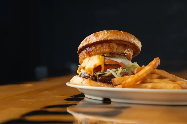 Close-up: Stacked gourmet burger with golden fries.