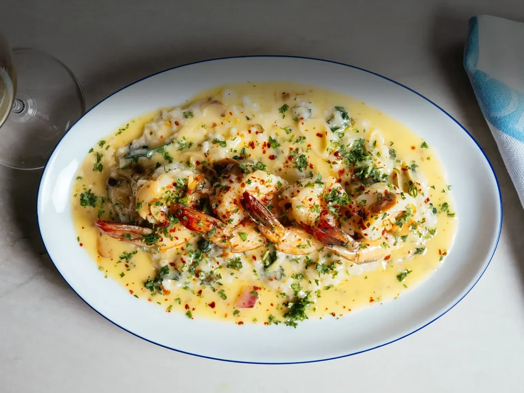 Shrimp in creamy yellow sauce with greens, herbs, and chili flakes.
