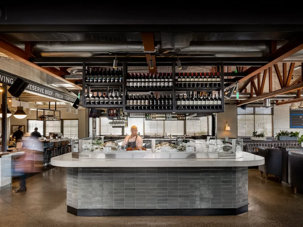 Modern restaurant interior with an ice-filled raw bar and wine rack.