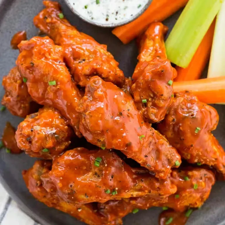 Buffalo chicken wings with creamy dip, carrot, and celery sticks.