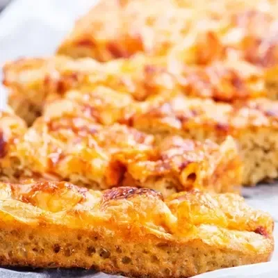 Golden-brown baked pasta slices with bubbly cheese and tomato sauce.