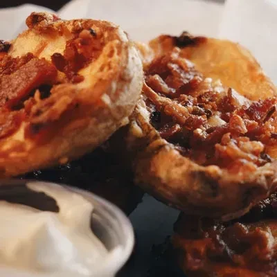 Close-up of golden baked goods with bacon and white dipping sauce.