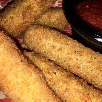 Golden-brown mozzarella sticks, herbs, marinara, on striped paper.
