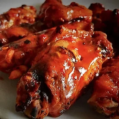 Glossy, reddish-orange chicken wings with charred spots.