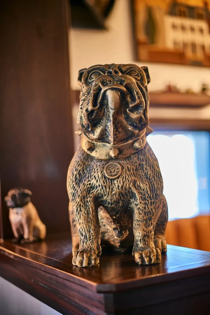 Detailed bronze bulldog statue with spiked collar and bird emblem.