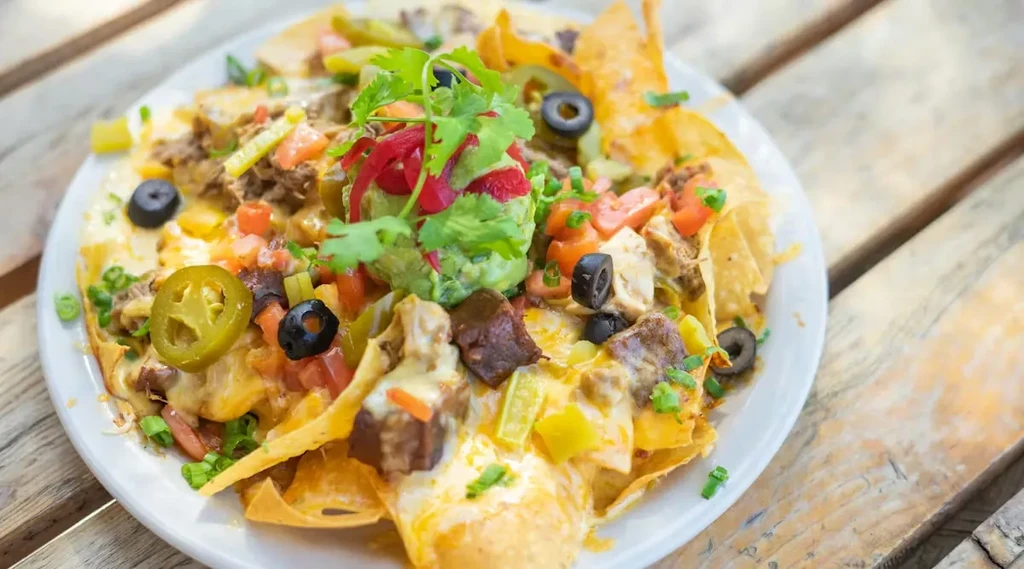 Nachos with melted cheese, meat, guacamole, tomatoes, jalapeños, and olives.