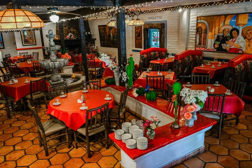 Empty Mexican-themed restaurant interior with colorful decor and a stone fountain.