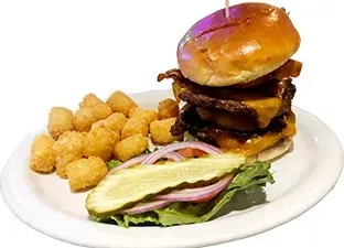 Stacked burger, tater tots, lettuce, onion, and a long dill pickle.