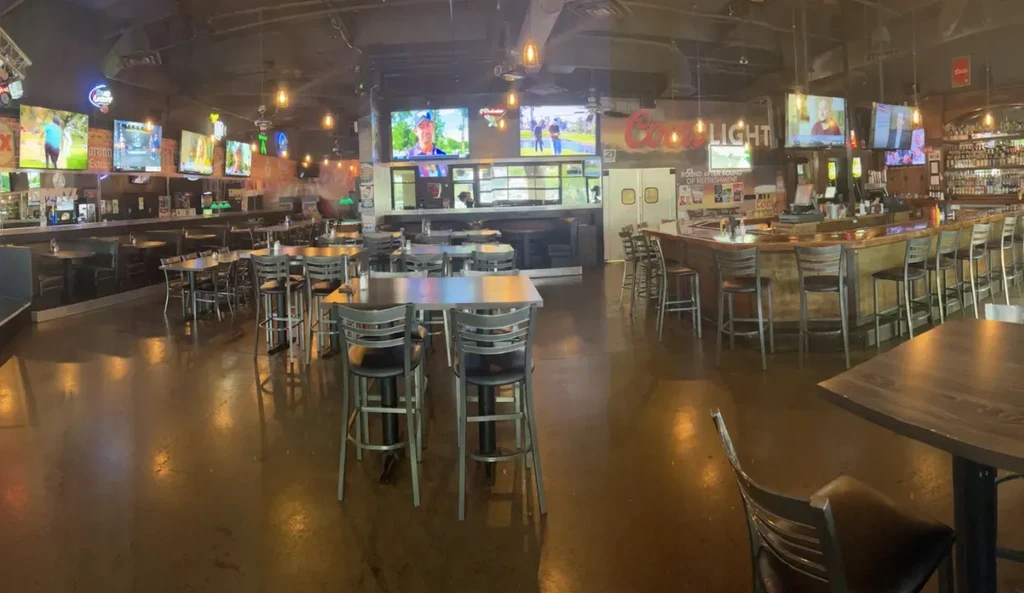 Casual sports bar interior with large bar, seating, and flat-screen TVs.