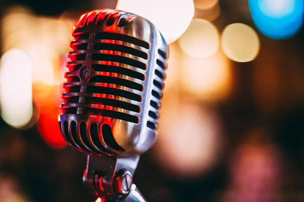 Chrome vintage microphone with warm red reflections and blurred lights.