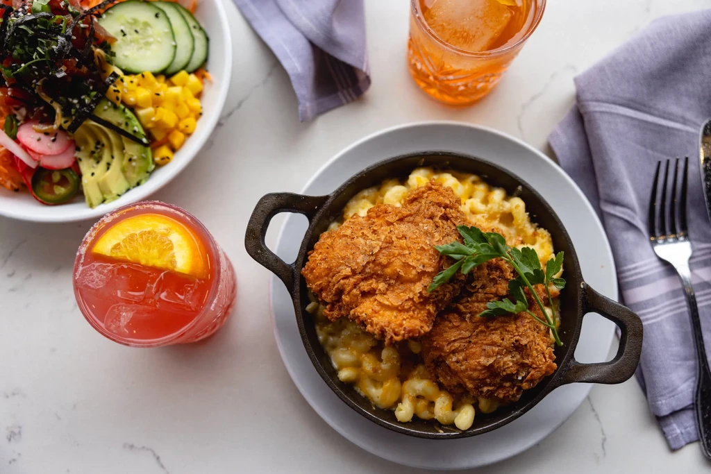 Overhead photo of mac and cheese with fried chicken, salad, and cocktails.