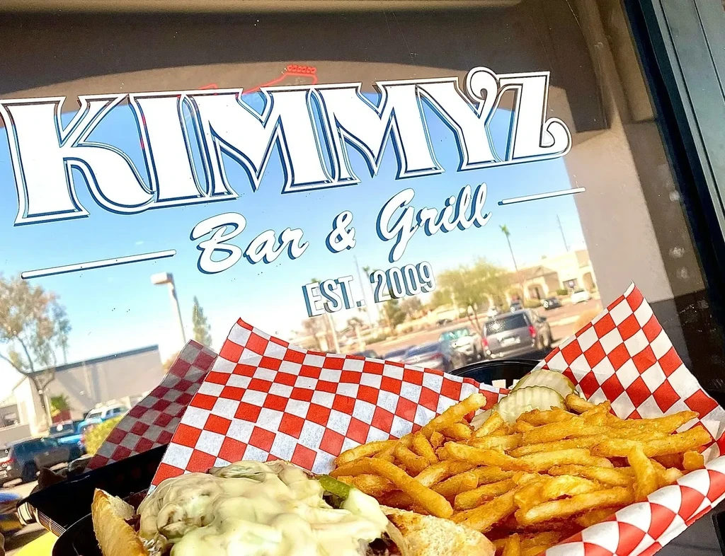 Cheeseburger and fries in a basket, KIMMYL Bar & Grill sign visible.