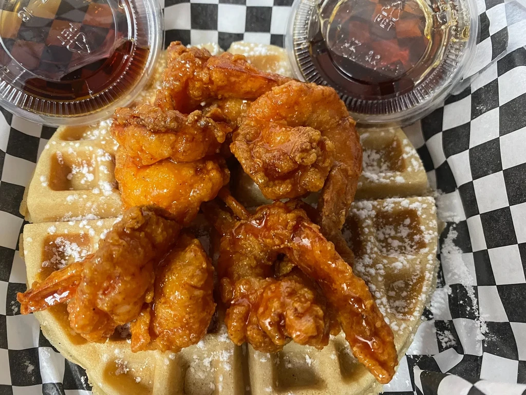 Golden waffle, sauced fried chicken or shrimp, powdered sugar, and two syrups.
