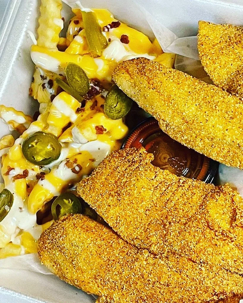 Loaded fries with jalapeños and crispy fried fish in takeout container.
