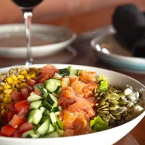 Colorful salad bowl with corn, tomatoes, salmon, and blue cheese.