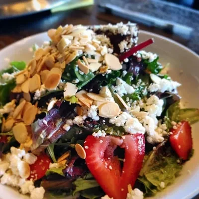 Vibrant mixed green salad with cheese, almonds, and strawberries.