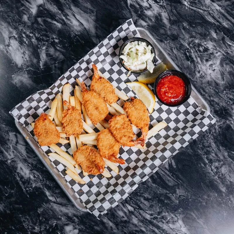 Fried shrimp, french fries, coleslaw, dipping sauce, lemon, and pickle.