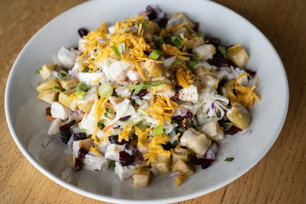 Overhead salad with chicken, coleslaw, cheese, and dried cranberries.