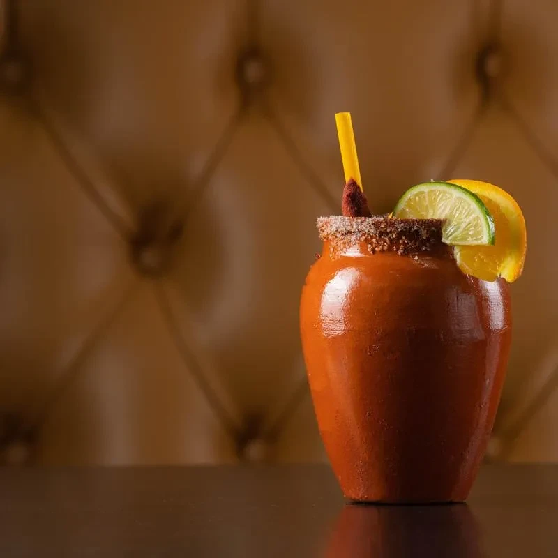 Rustic drink in clay pot with sugared rim, straw, and citrus.