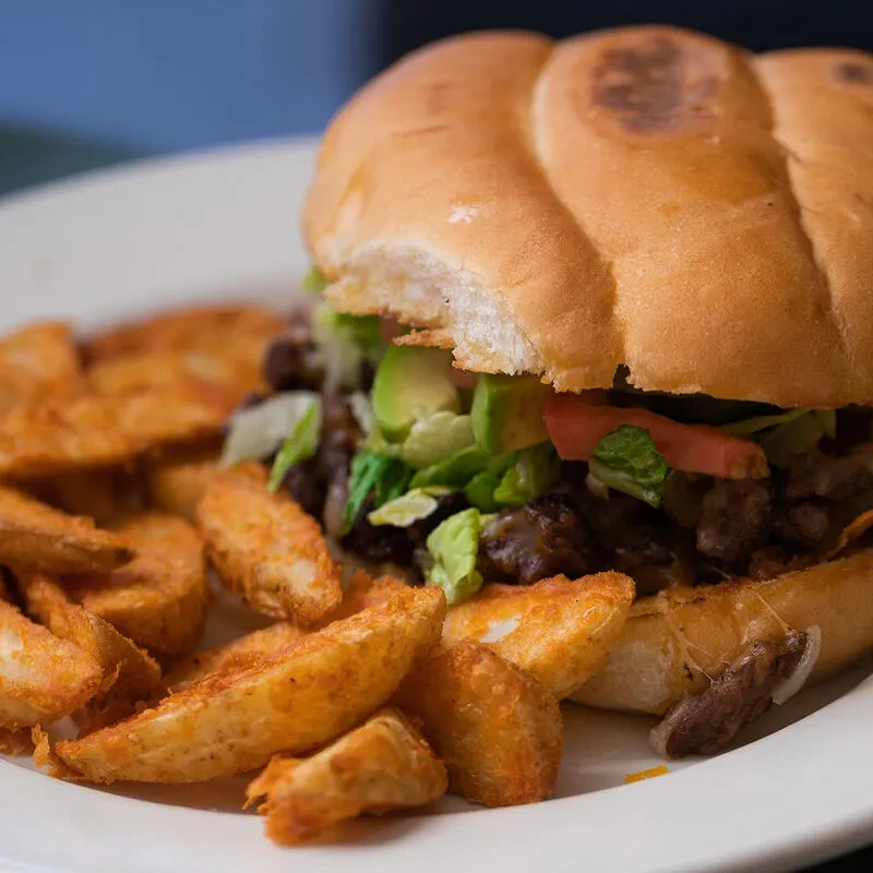 A substantial sandwich with meat, cheese, avocado, and seasoned potato wedges.