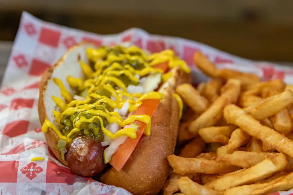 Hot dog with toppings, crinkle-cut fries, checkered liner.