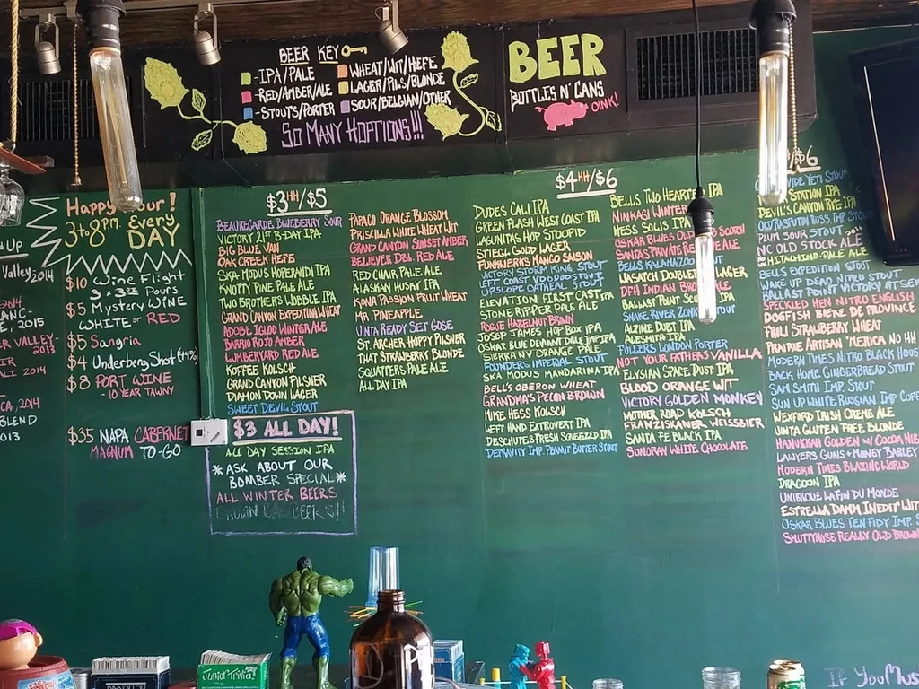 Detailed chalkboard menu shows numerous craft beers and wines at a bar.