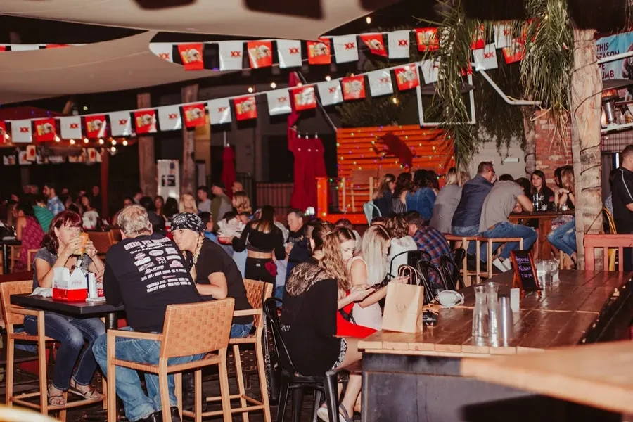 Crowded outdoor restaurant at night, lit by warm string lights.