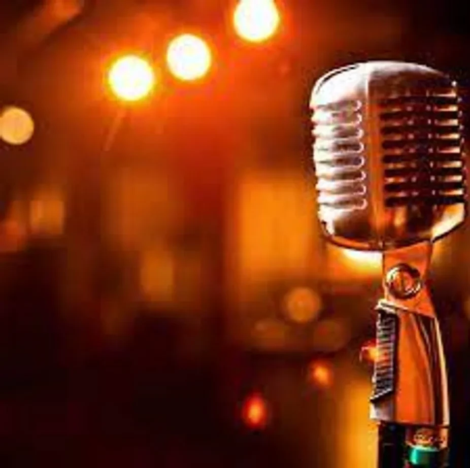 Vintage metallic microphone against a warm, blurred lights background.