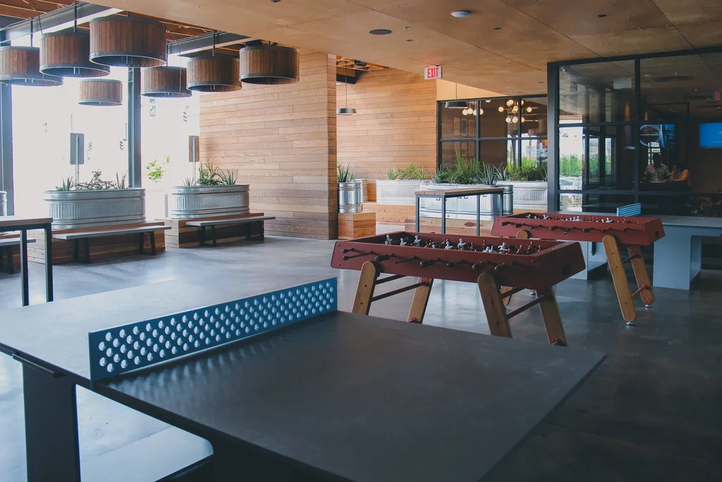 Spacious modern interior with ping-pong, foosball tables, plants, and natural light.