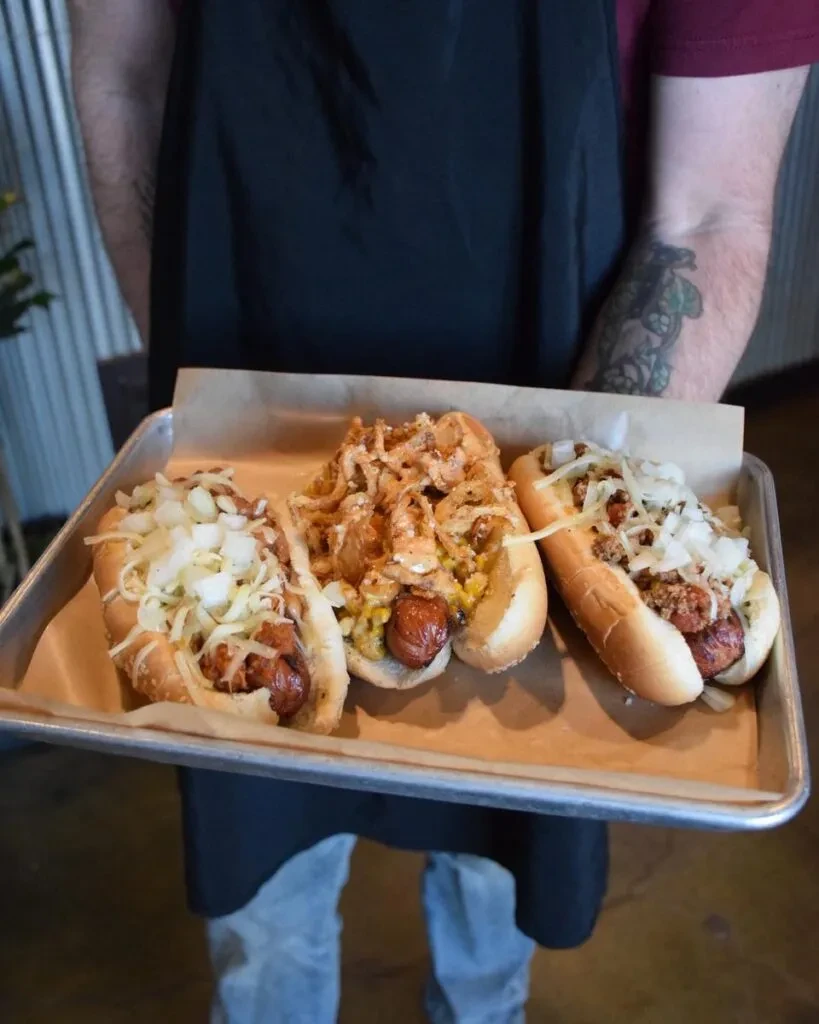 Three gourmet hot dogs topped with onions, chili, and crispy onions.