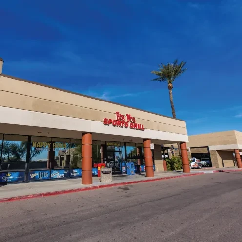 Exterior of Vic's VIP Sports Grill with red sign, under blue sky.