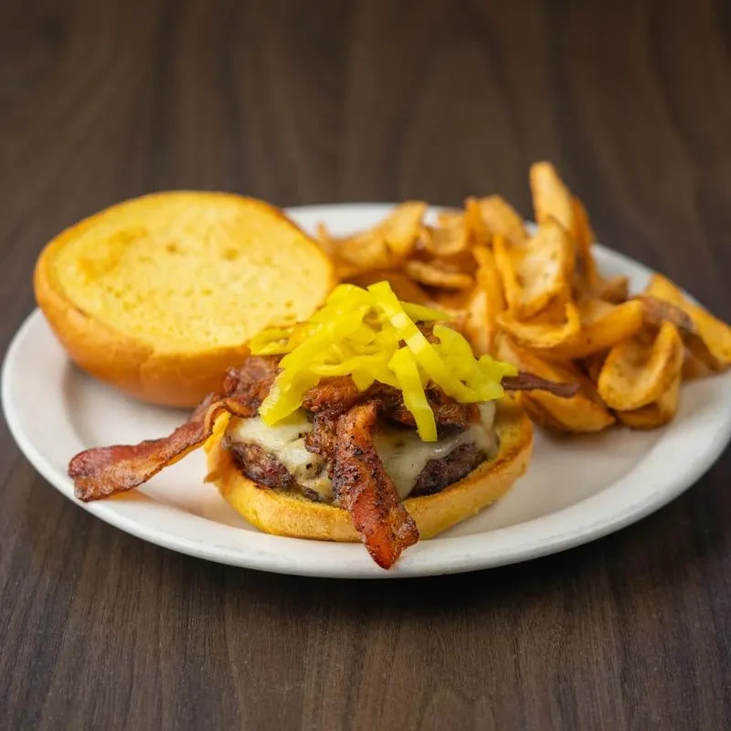 Burger with melted cheese, bacon, pickled peppers, and waffle fries.