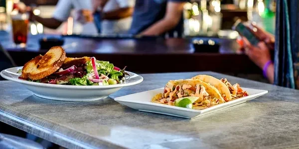 Two plates of food: sandwich with salad and tacos in a restaurant.
