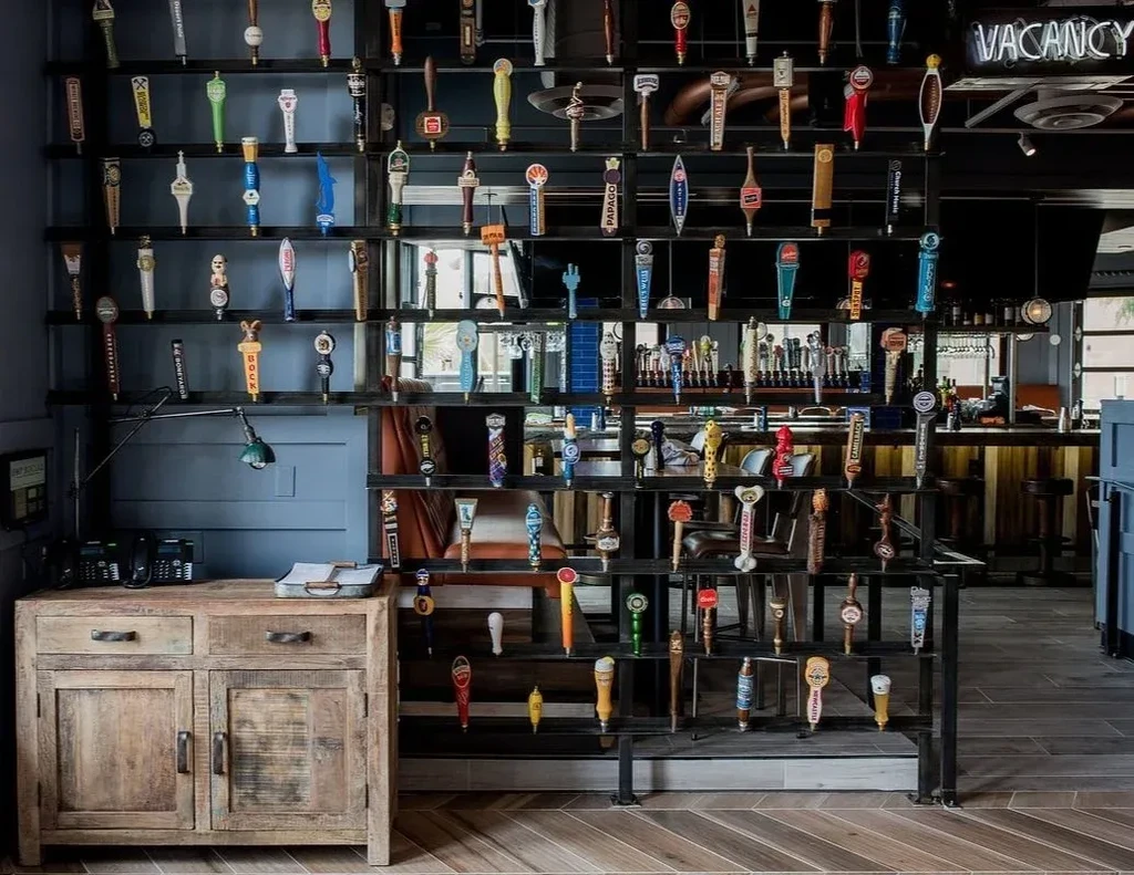 Meticulously arranged beer tap handles in a bar with a 'VACANCY' neon sign.