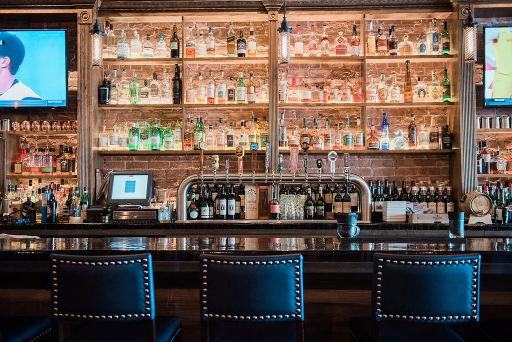 Bar with illuminated liquor bottles, beer taps, and sports on TV.