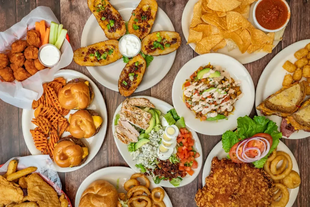 Overhead view of a dark table with various casual restaurant dishes.