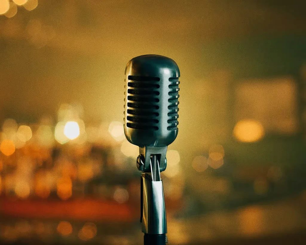 Vintage silver microphone in focus with warm, blurred background lights.