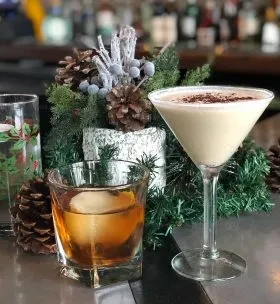 Two festive drinks and winter holiday decor on a bar counter.