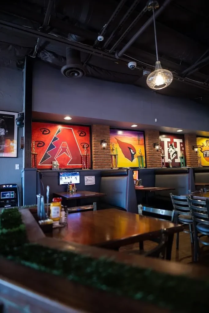 Warm, industrial-chic sports bar interior with booths and team logos.