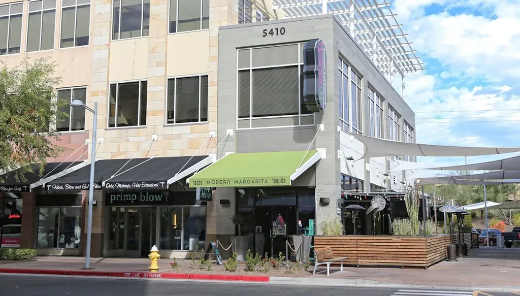 Exterior view of 5410 Tacos Modern restaurant with green awning and patio.