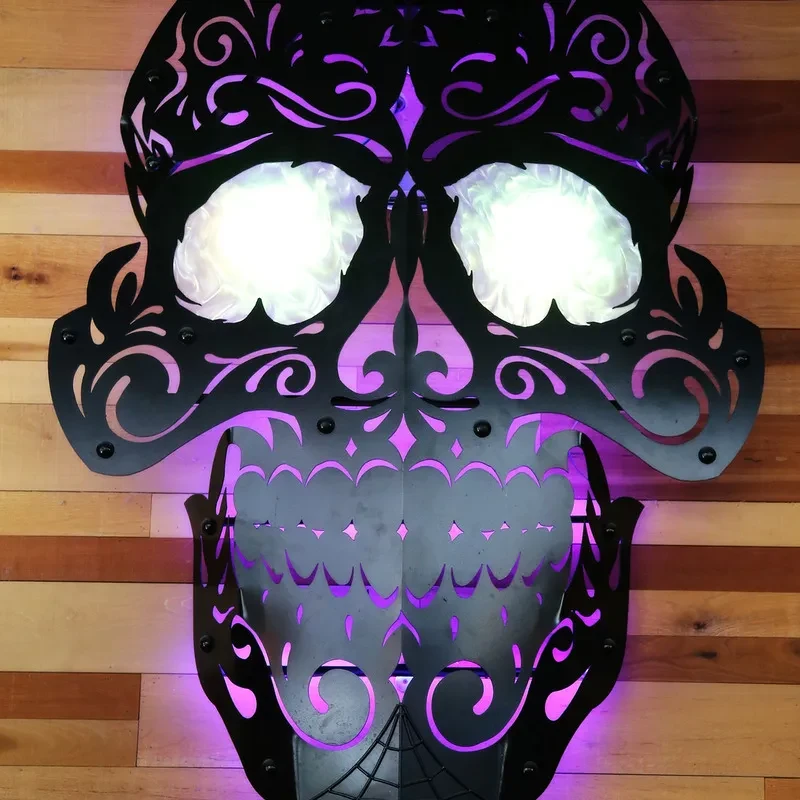 Ornate dark metal skull with glowing white eyes and purple backlighting.