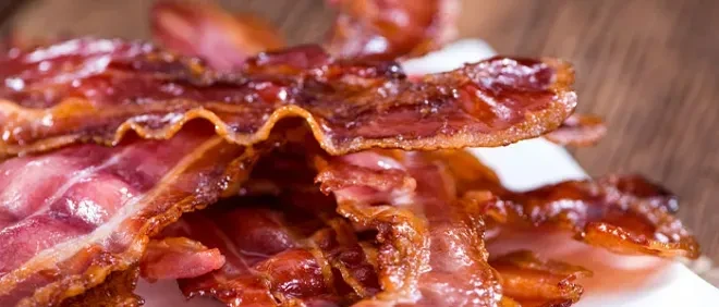 Close-up of several crisp, cooked bacon strips piled together.
