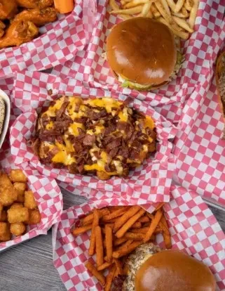 Overhead view of loaded fries, burgers, chicken wings, and tots.