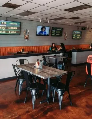 Sports bar interior: tables, orange booths, TVs with sports scores and news.